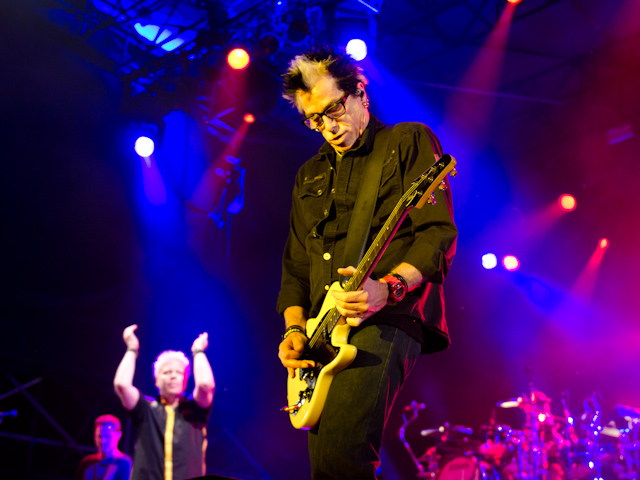 The Offspring guitarist performing beneath concert lights at Echo Beach in Toronto.